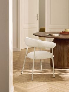 a white chair sitting next to a wooden table on top of a hard wood floor