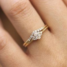 a woman's hand with a diamond ring on top of her finger and an engagement band