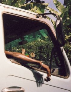 the side view mirror of a white truck parked in front of a tree filled field