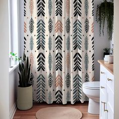 a bathroom with a shower curtain, toilet and plant on the floor in front of it