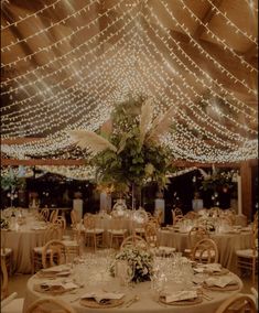 the tables are set up for an event with white linens and lights strung overhead