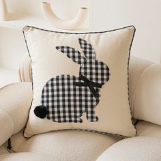 a black and white pillow with a rabbit on it's back sitting on a chair