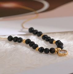 Introducing our captivating black crystal cubic zirconia beaded necklace, delicately set on an 18K gold PVD chain. This stunning piece combines the allure of black crystals with the elegance of fine craftsmanship. Each black crystal cubic zirconia bead represents strength, protection, and healing, adding a touch of mystique and symbolism to the necklace. The beads are meticulously threaded onto a delicate 18K gold PVD chain, creating a harmonious contrast between the dark crystals and the luxuri Elegant Black Crystal Necklace With Beaded Chain, Black Crystal Beaded Necklace With Round Beads, Elegant Black Crystal Necklace With Gemstone Beads, Elegant Black Round Bead Crystal Necklaces, Black Crystal Beaded Necklaces For Jewelry Making, Black Crystal Beaded Necklaces For Gift, Black Crystal Beaded Necklace For Gift, Elegant Black Crystal Necklace With Clavicle Chain, Crystal Necklace With Black Beads As A Gift