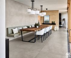 a dining room table with white chairs next to a long bench in front of a wall