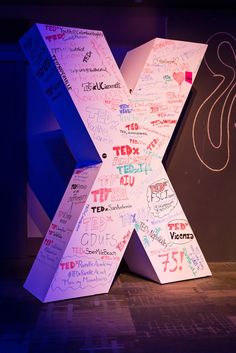 a large x made out of letters with writing all over it on a stage area