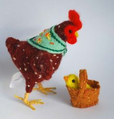 a red and white chicken next to a basket with a yellow duckling in it