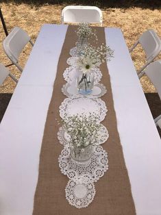 the table is decorated with white flowers and burlock on it's runners