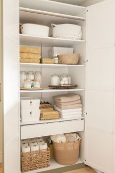 an organized pantry with white shelves and wicker baskets