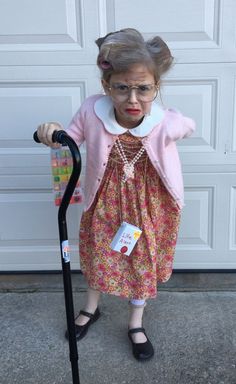 an old woman wearing glasses and holding a scooter in front of a garage door