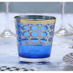 a blue glass with gold rim sitting on a table next to wine glasses and plates