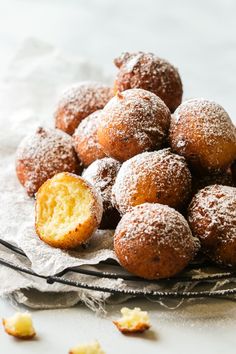 a pile of powdered doughnuts sitting on top of a white plate with the words zeppole, italian ricotta doughnuts