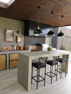 an outdoor kitchen with bar stools next to the counter and cabinets in front of it