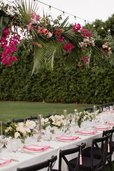 a long table is set with pink and white flowers, greenery, and candles