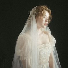 a woman in a wedding dress with a veil on her head is looking off to the side