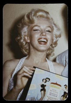 an old photo of marilyn monroe holding a book