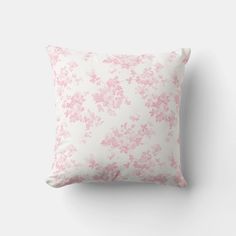 a pink and white floral pillow on a wall