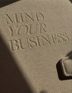 the word mind your business written in white on a beige carpeted surface with an open wallet