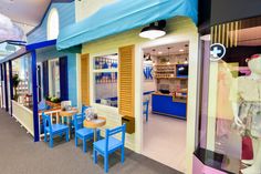 the inside of a children's store with blue chairs and tables in front of it