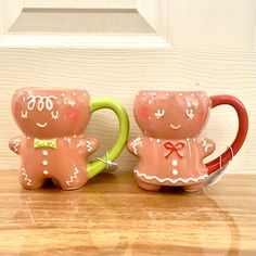 two ceramic mugs sitting next to each other on a wooden table with a white door in the background