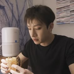 a person sitting at a table with a sandwich in their hand and a speaker on the wall behind them