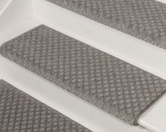 two gray rugs sitting on top of a white stair case next to each other