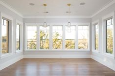 an empty room with large windows and hard wood flooring in the center is shown