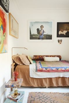 a bed sitting in a bedroom next to two pictures on the wall and rugs