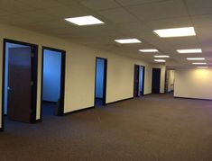 an empty room with three doors and no one in the room on the far side