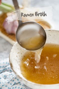 a spoon is pouring broth into a bowl