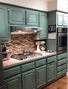 an image of a kitchen with green cabinets and stainless steel appliances on the counter top