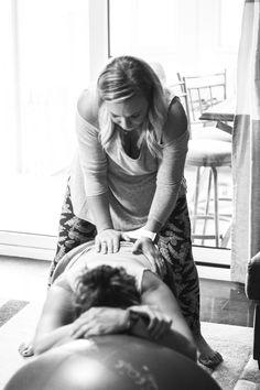 a woman getting a back massage from another woman in a room with large windows and chairs