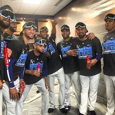 a group of baseball players pose for a photo in front of a locker room wall