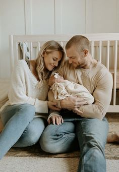 a man and woman sitting on the floor holding a baby