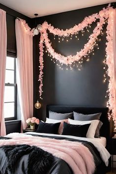 a bedroom decorated in pink and black with lights strung from the ceiling, bed linens on