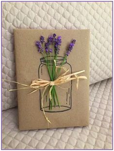 a card with lavender flowers in a mason jar tied to twine on top of a bed