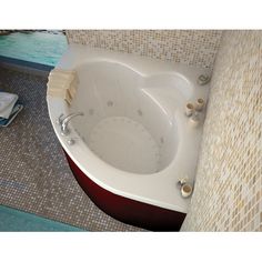 a bathroom with a large jacuzzi tub next to a tiled wall and floor