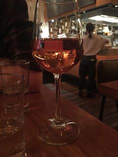 a glass of wine sitting on top of a wooden table