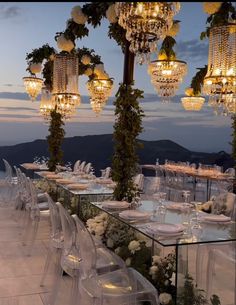 an outdoor dining area with chandeliers and tables set up for a formal function