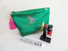 Handmade clutch bag made out of a green satin butterfly fabric, with a contrasting bright pink cotton lining. The bag has a green zipper closure with a pink tassel clipped on the zipper pull. Approximate size: 6.5in x 9.5in (16.5cm x 24cm). Materials: Satin fabric, cotton fabric, padding, zipper and tassel. This is a perfect size for phone, keys and purse, or as a cosmetic bag. I like to use it as a travel bag. By keeping all the essentials in one place, nothing gets forgotten. Please see the th Green Clutch Evening Bag For Gift, Butterfly Fabric, Butterfly Motif, Satin Clutch, Fabric Butterfly, Handmade Clutch, Green Handbag, Pink Tassel, Green Satin