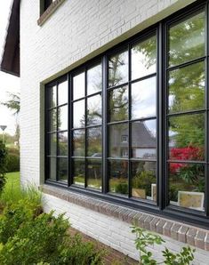 a white brick building with black windows and plants