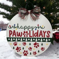 a sign that says happy paws and holidays hanging from a christmas tree in the snow