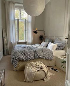 a bedroom with a large bed and lots of pillows on the floor next to a window