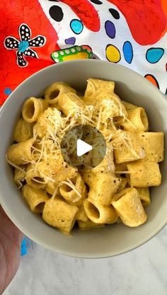 a bowl filled with pasta and cheese on top of a marble countertop next to a colorful towel