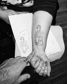 two people holding hands with tattoos on them