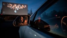 a rear view mirror on a car with a movie screen in the back window at night