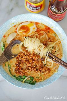 a bowl filled with noodles and meat next to some condiments on a table