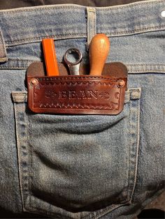 a pair of scissors and other tools in a brown leather pocket on someone's jeans