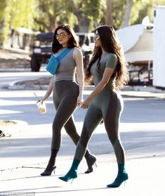 two women in grey bodysuits and high heeled boots walking down the street