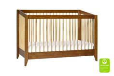 a wooden crib with white sheets on it