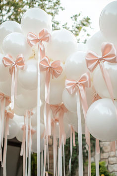 many white balloons with pink bows tied to them